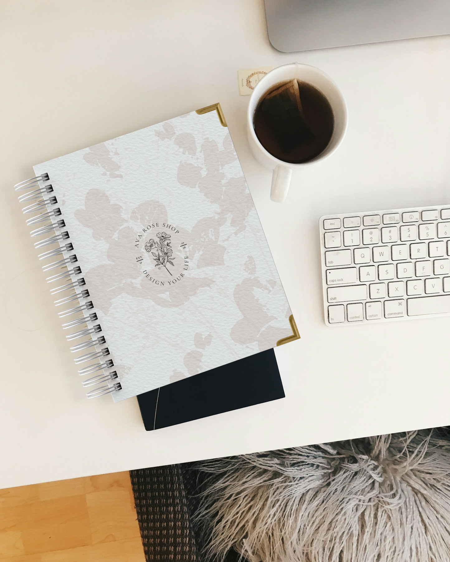 Floral planner with sunglasses, pen, and coffee cup on a white surface