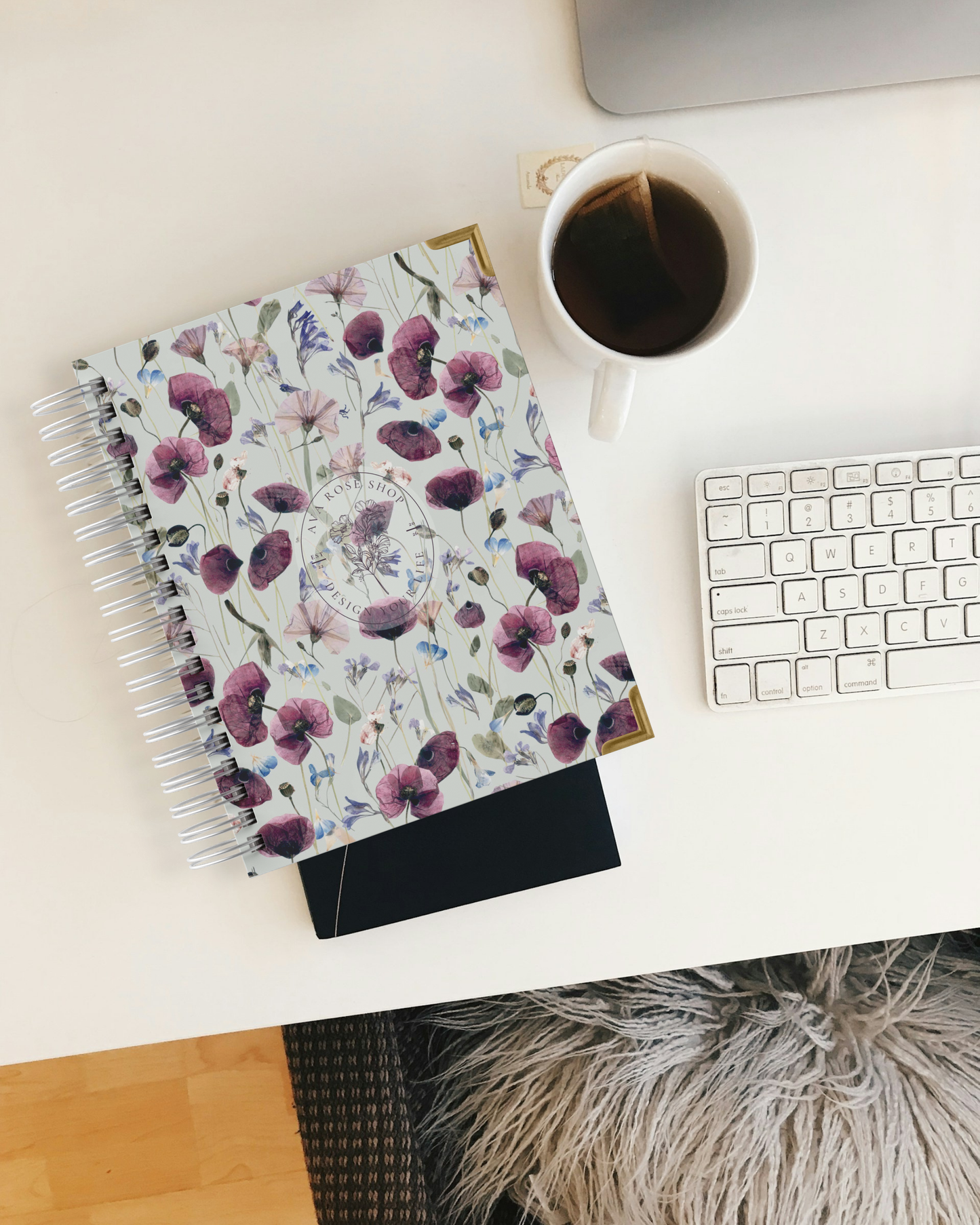 Floral planner, coffee cup, and keyboard on a desk