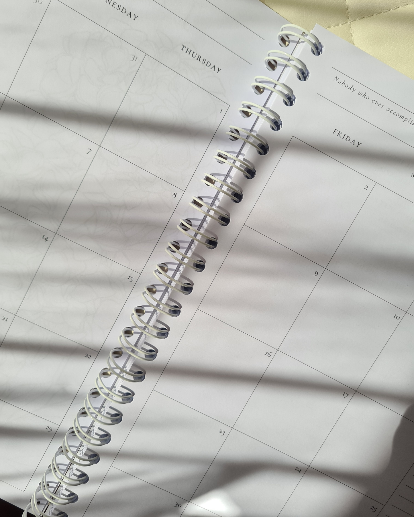 Spiral-bound monthly planner on a grid-patterned surface