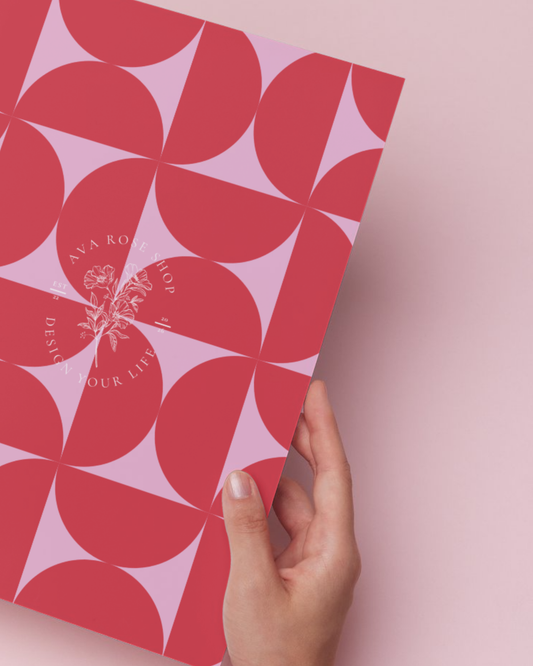 Hand holding a pink and red patterned planner against a pink background